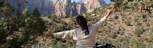 Person facing canyon with arms spread